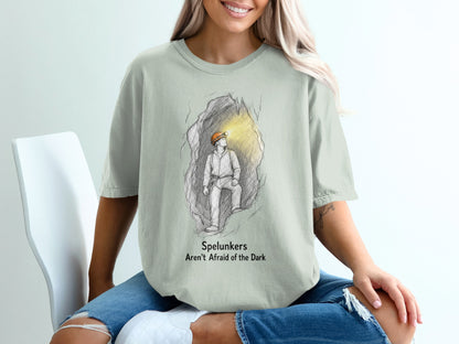 Light gray t-shirt with a sketch of a spelunker in a cave with text "Spelunkers Aren't Afraid of the Dark."