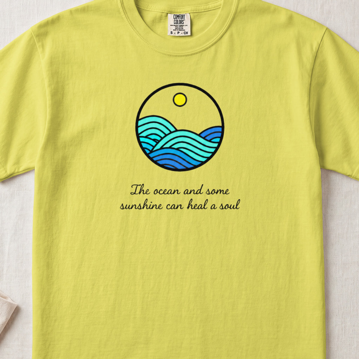 Yellow crewneck t-shirt featuring a circular ocean graphic and the text "The ocean and some sunshine can heal a soul."
