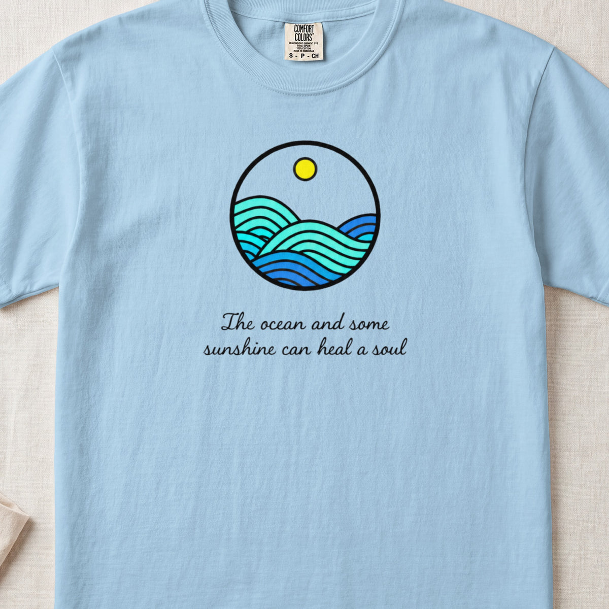 Light blue t-shirt with a round ocean graphic and text that reads The ocean and some sunshine can heal a soul.