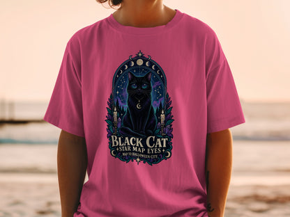 Pink t-shirt with a black cat, moon phases, stars, and text "Black Cat Star Map Eyes".