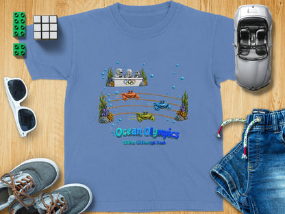 Blue t-shirt with "Ocean Olympics 100m Sideways Dash" and cartoon crabs racing.