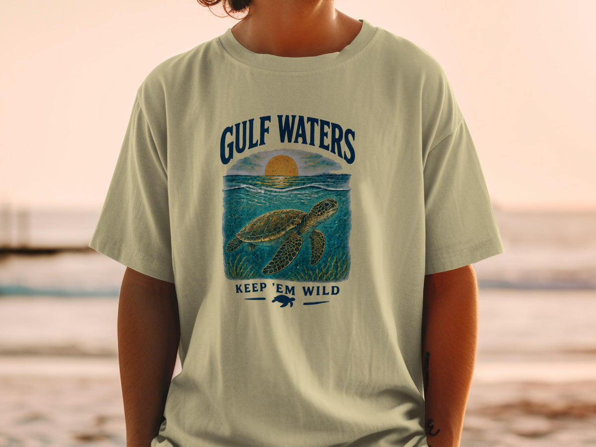 T-shirt with Gulf Waters graphic, sea turtle, and sunset. Keep 'Em Wild text.