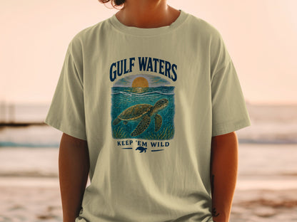 T-shirt with Gulf Waters graphic, sea turtle, and sunset. Keep 'Em Wild text.