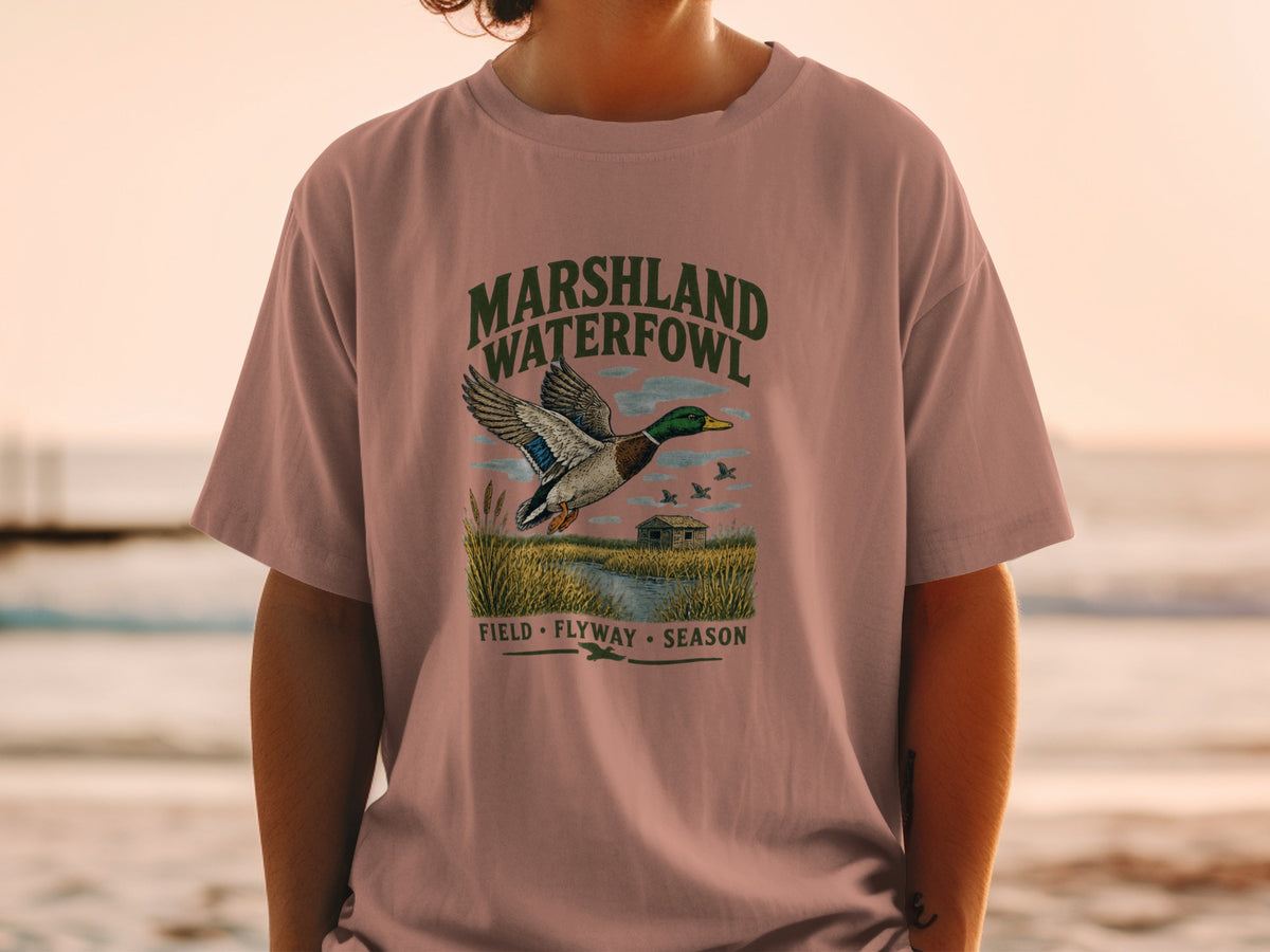 T-shirt graphic with mallard duck, marsh, and text "MARSHLAND WATERFOWL".