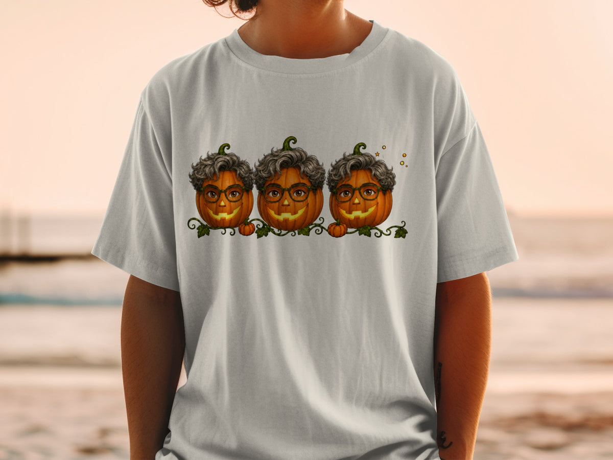 Three smiling pumpkins with glasses and curly hair on a shirt.