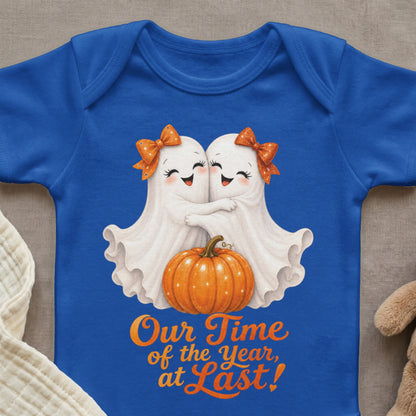 Two cartoon ghosts hug beside a pumpkin on a blue bodysuit with text.