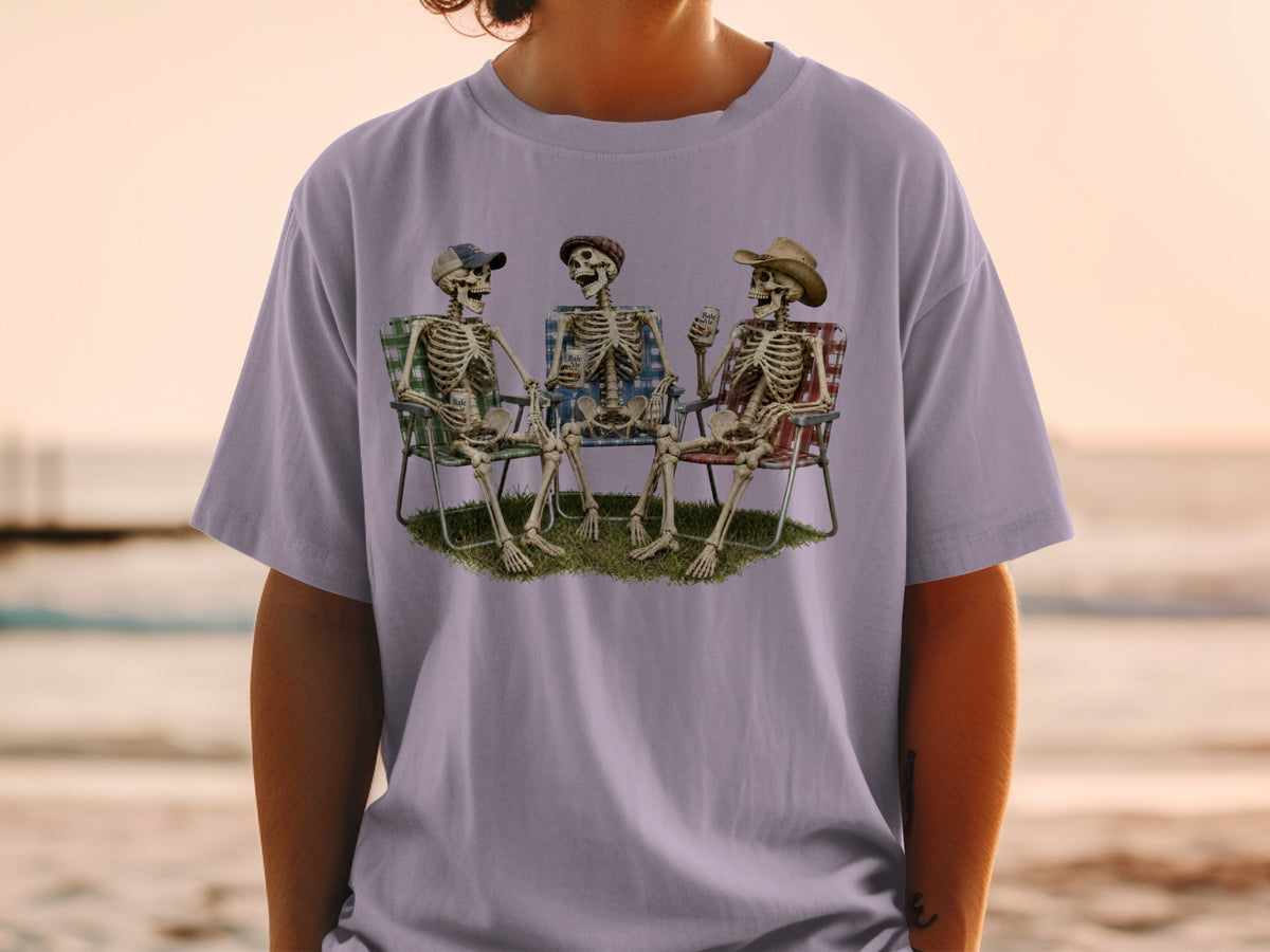 Three skeletons sit in lawn chairs on grass, holding drinks.