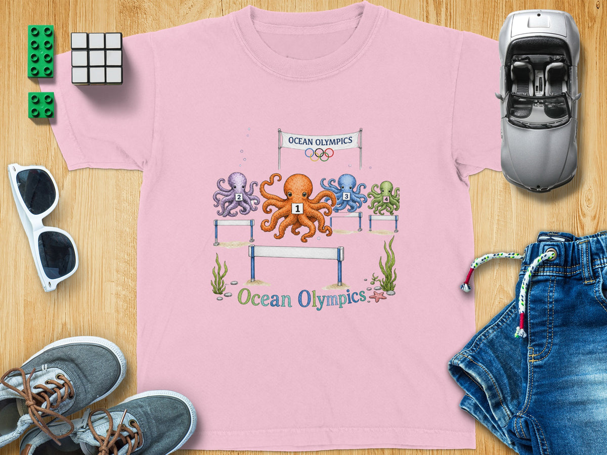 Pink t-shirt with cartoon octopuses racing over hurdles under an "Ocean Olympics" banner.