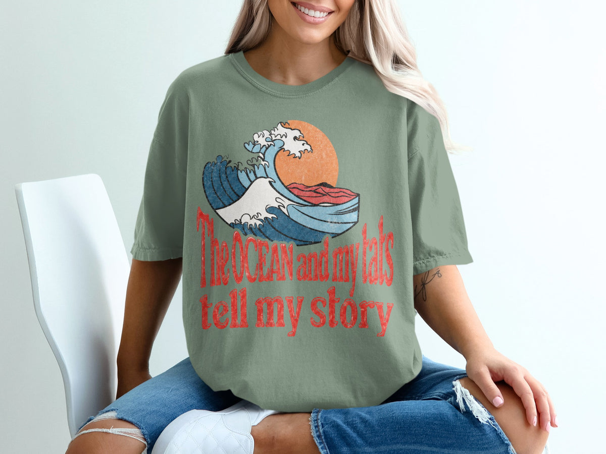 Green t-shirt with graphic of a wave and text "The OCEAN and my tats tell my story."