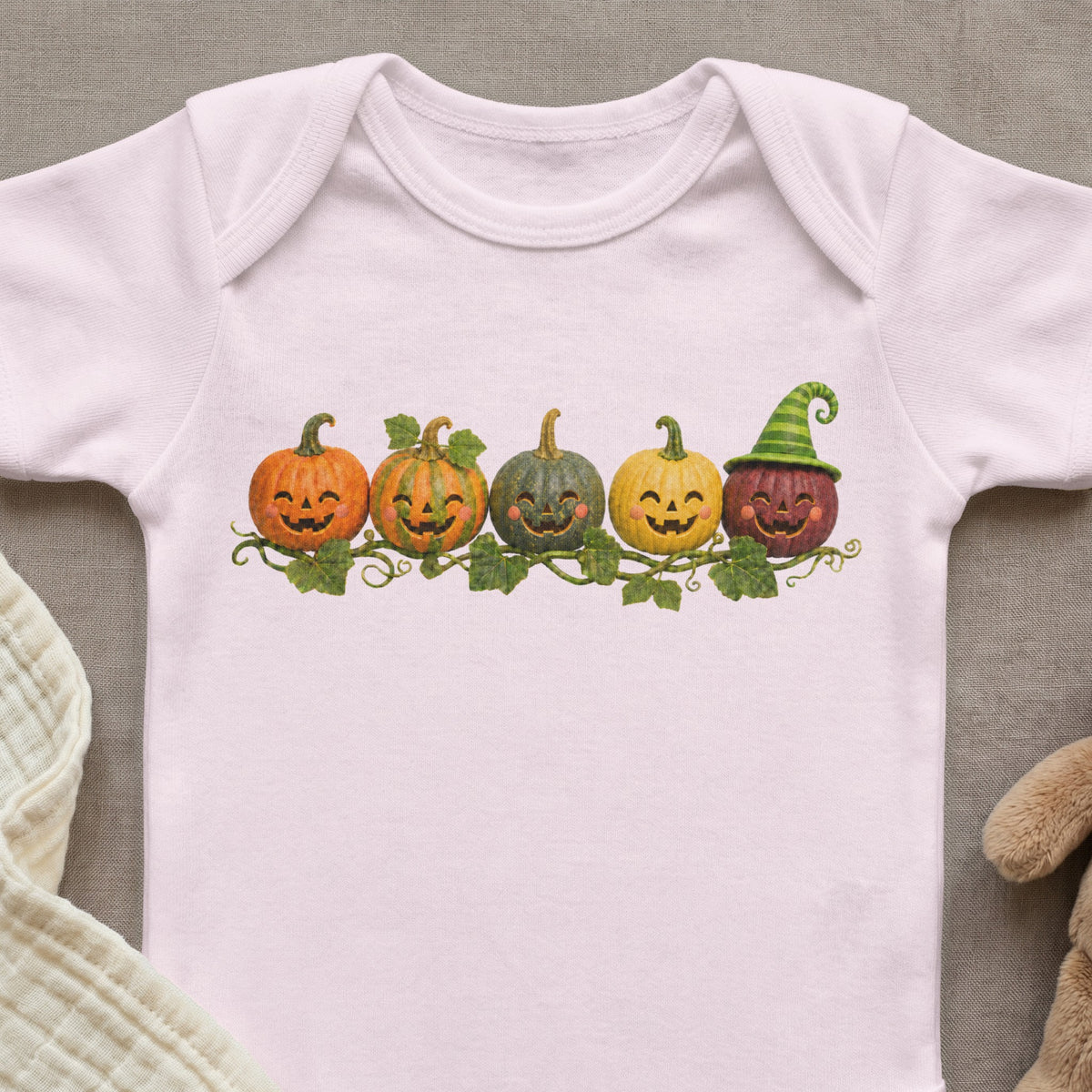 Pink baby onesie with five cartoon pumpkins and leaves graphic.