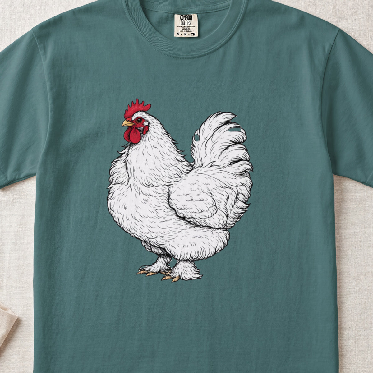 A green t-shirt featuring a detailed illustration of a white rooster with a red comb.