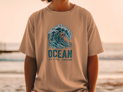 Brown t-shirt with a graphic of a breaking wave and text "OCEAN AIR SALT FREEDOM".