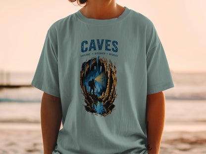 T-shirt graphic showing a caver exploring a cave with text "CAVES EXPLORE DISCOVER RESPECT".