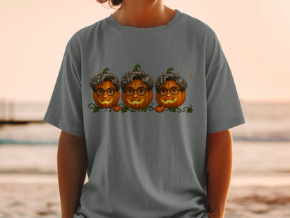 Three cartoon pumpkins with glasses and curly hair on a grey t-shirt.