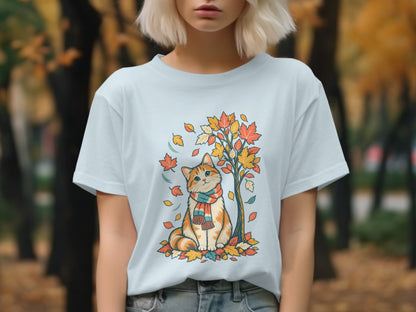 Light blue t-shirt with a cat wearing a scarf surrounded by autumn leaves.