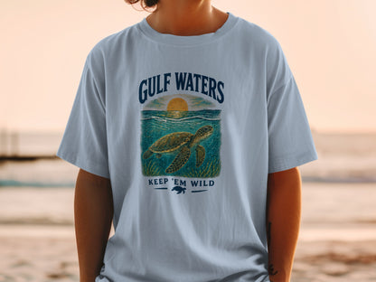 Light blue t-shirt with a sea turtle graphic and text "GULF WATERS KEEP 'EM WILD."