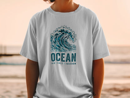 White t-shirt with a blue ocean wave graphic and text "OCEAN AIR SALT FREEDOM".