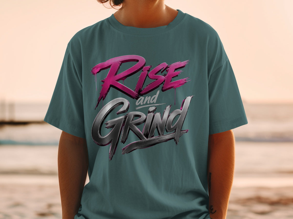Teal t-shirt with metallic pink and silver "Rise and Grind" text graphic.