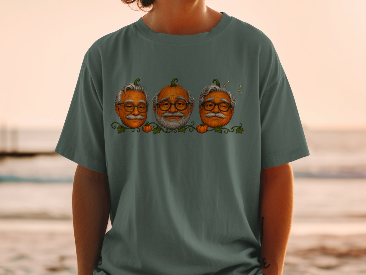 Three pumpkins with elderly men's faces and glasses on a green t-shirt.