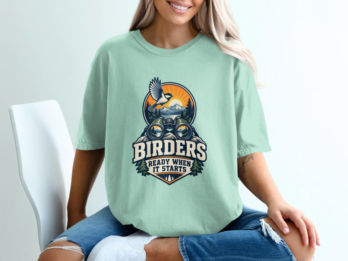Mint t-shirt with graphic of binoculars, mountains, bird, and text "BIRDERS READY WHEN IT STARTS".