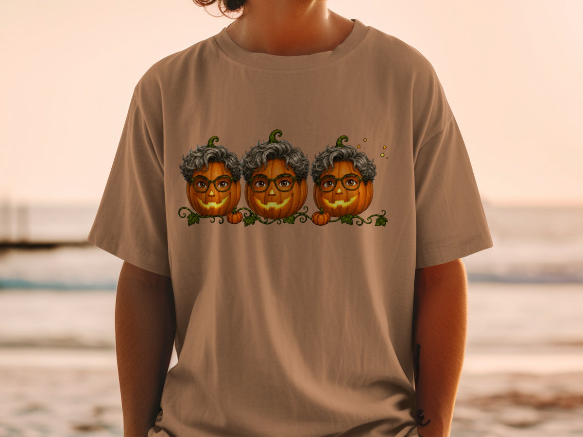 Three smiling pumpkins with curly gray hair and glasses on a brown t-shirt.