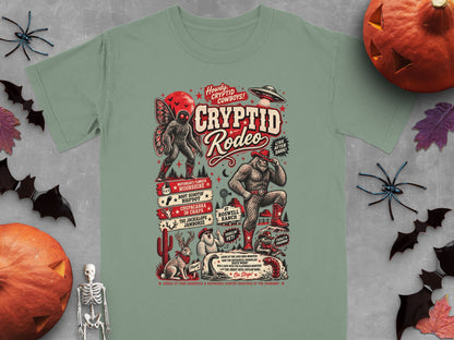 Cryptid Rodeo graphic with Mothman, Bigfoot, Yeti, Jackalope, and UFO on green t-shirt.