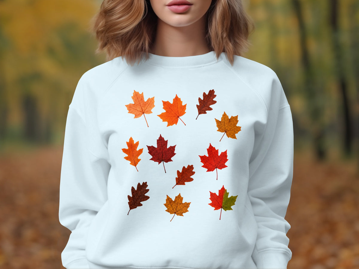White sweatshirt with an assortment of autumn leaf designs on the chest.