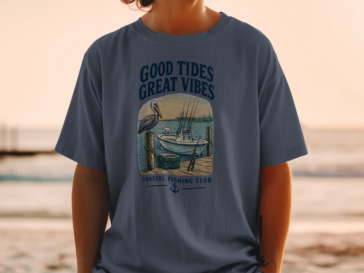 T-shirt graphic with pelican, boat, and text "GOOD TIDES GREAT VIBES COASTAL FISHING CLUB".