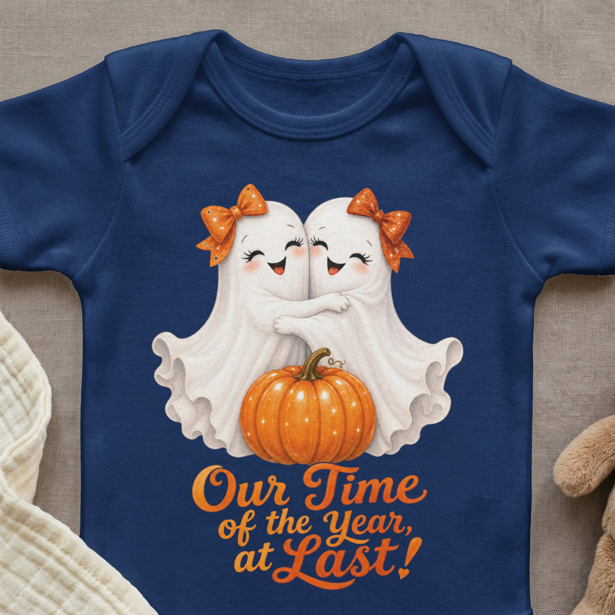 Two cute ghosts hug by a pumpkin, with text that reads "Our Time of the Year, at Last!"