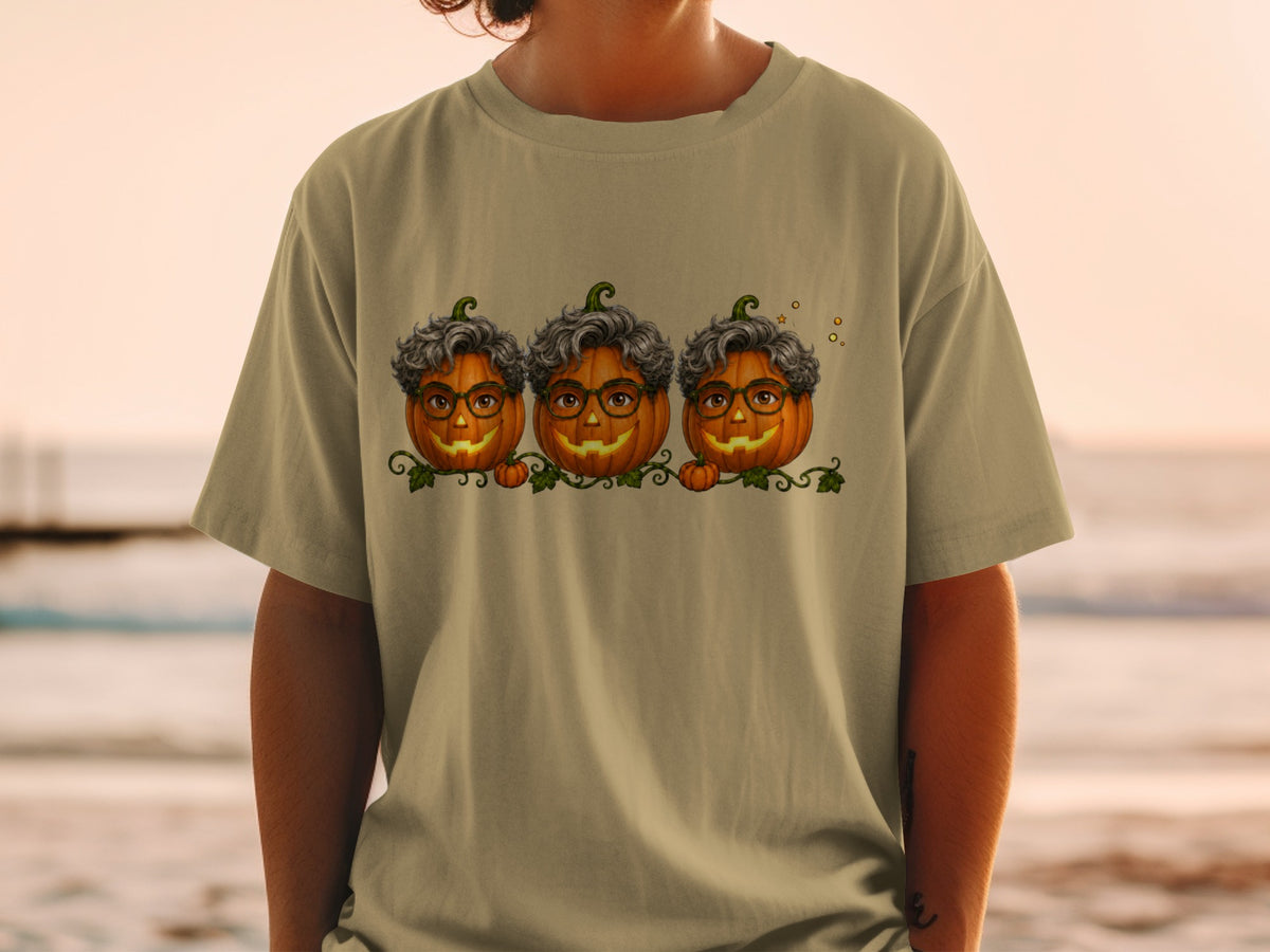 Three pumpkins with glasses and curly hair wear a vine design on a tan shirt.