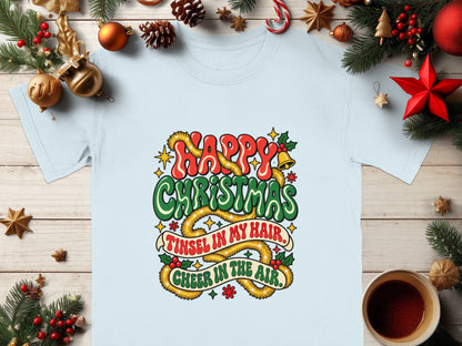 Light blue t-shirt with "Happy Christmas, Tinsel in My Hair, Cheer in the Air" holiday graphic.