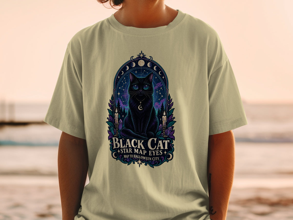 Black cat with starry eyes and celestial design on a tan t-shirt.