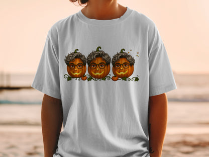 Three cartoon pumpkins with curly hair and glasses on a t-shirt.