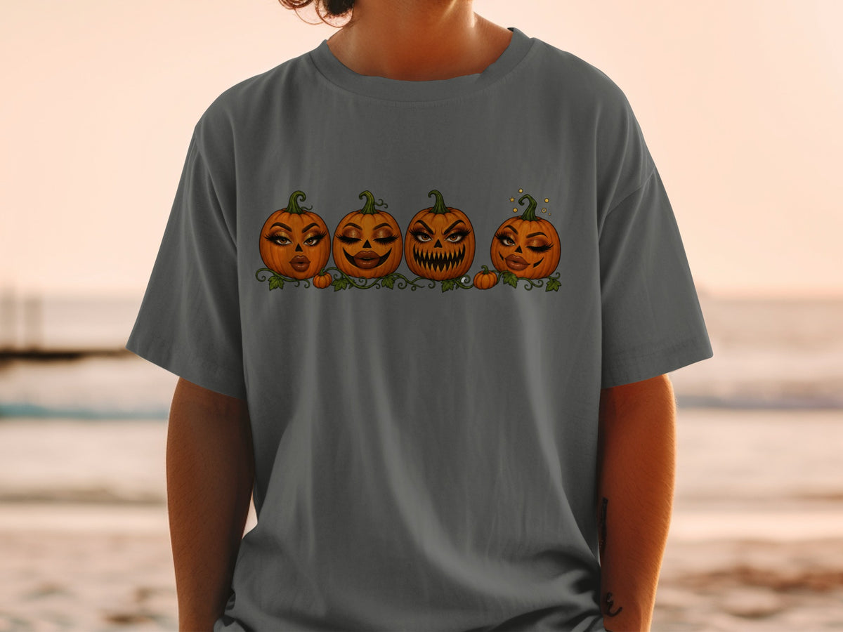 Four anthropomorphic pumpkins with makeup on a dark grey t-shirt.