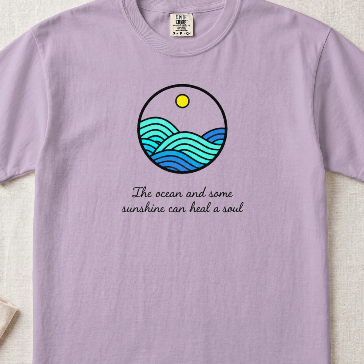 Light purple t-shirt featuring a circular ocean graphic with a sun and the text "The ocean and some sunshine can heal a soul."