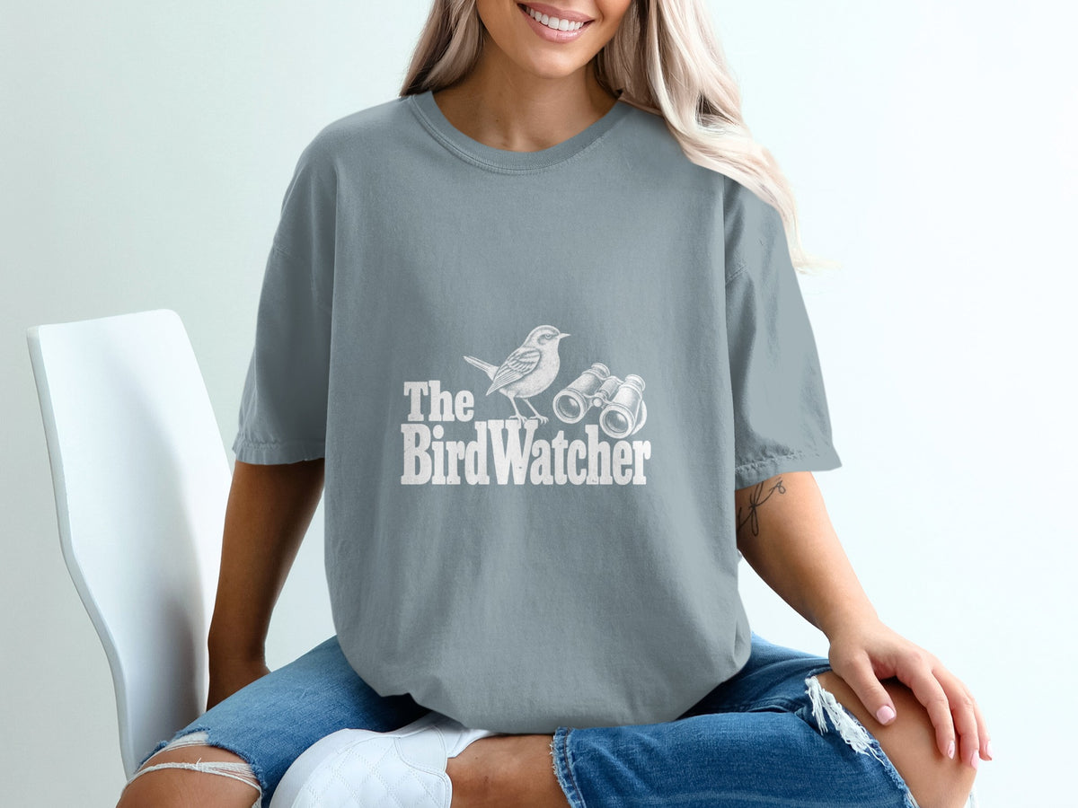 Grey t-shirt with white text and graphic: "The Bird Watcher" with a bird and binoculars.