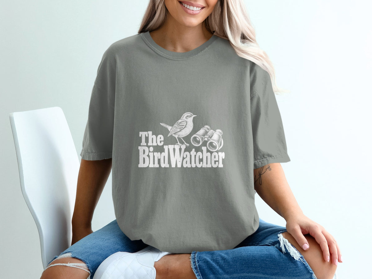 Grey t-shirt with white graphic of a bird and binoculars, text "The Bird Watcher".