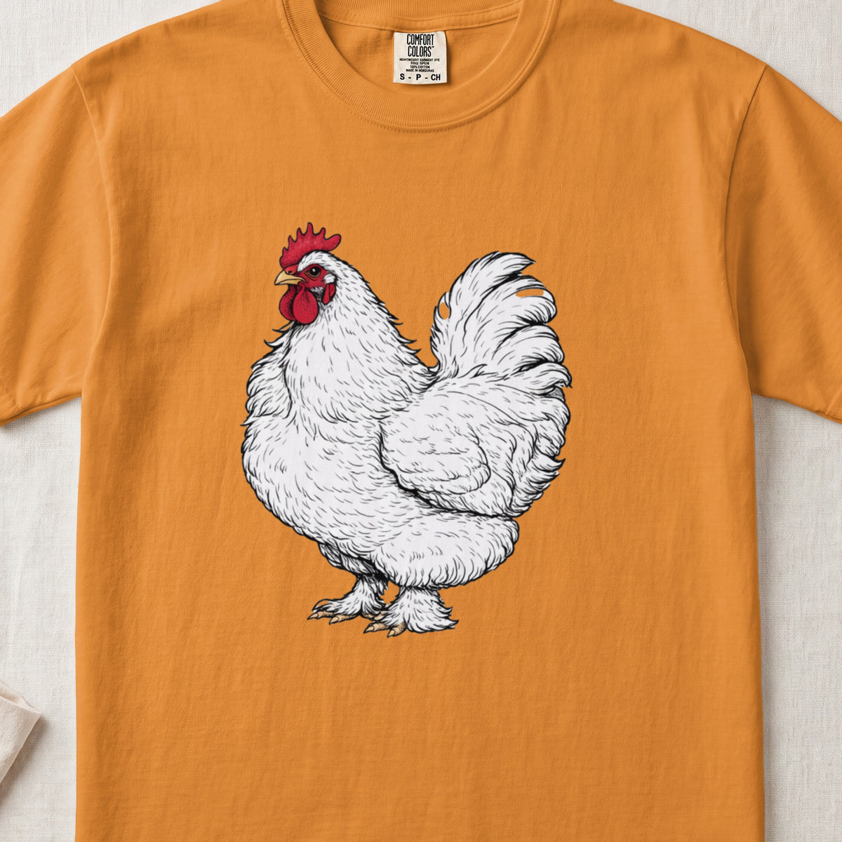 An orange crewneck t-shirt featuring an illustration of a detailed white rooster centered on the chest.