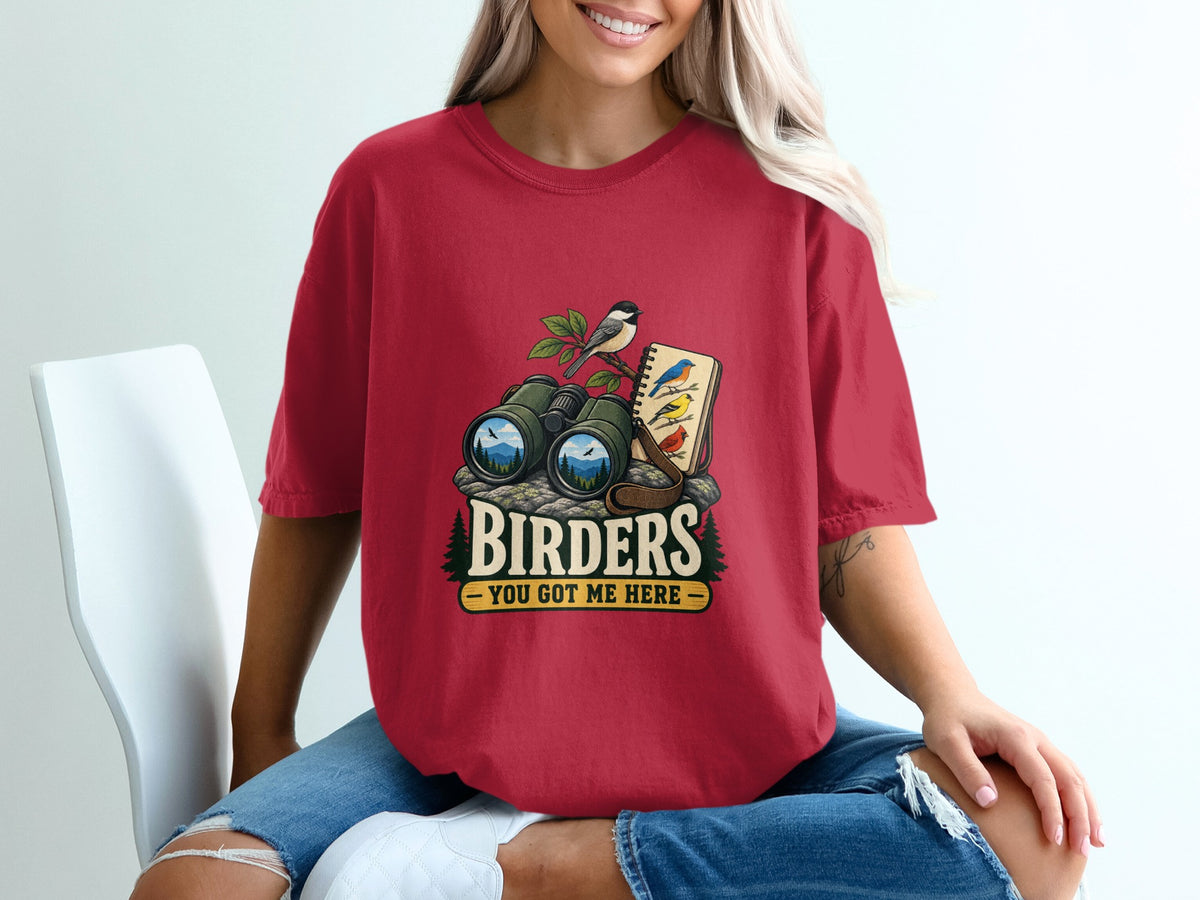 Red t-shirt graphic with binoculars, bird on a branch, and notebook with text "Birders You Got Me Here."