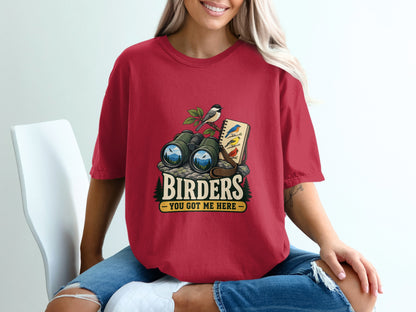Red t-shirt graphic with binoculars, bird on a branch, and notebook with text "Birders You Got Me Here."