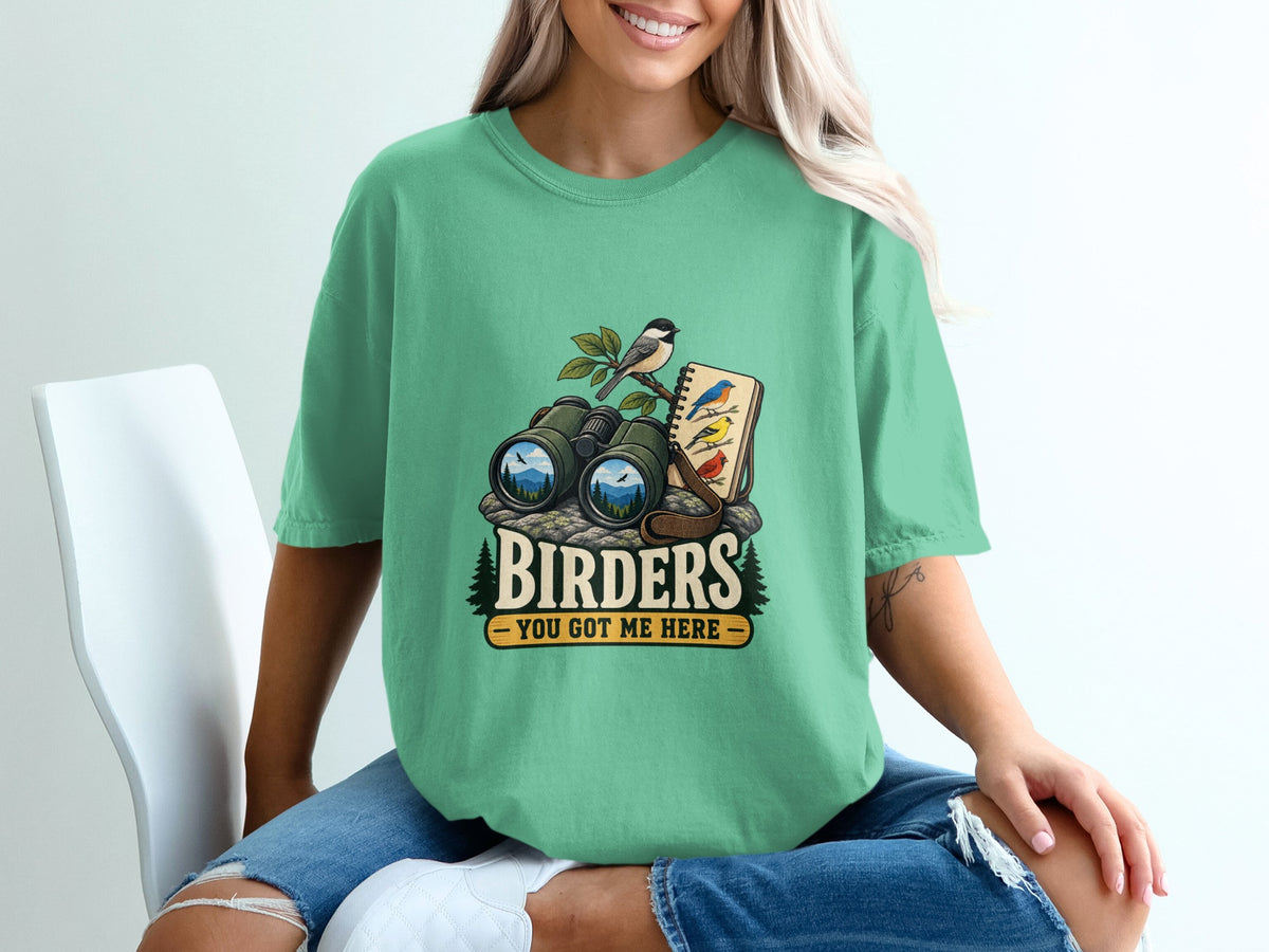 Binoculars, birds on a branch, and a notebook with text "BIRDERS YOU GOT ME HERE".