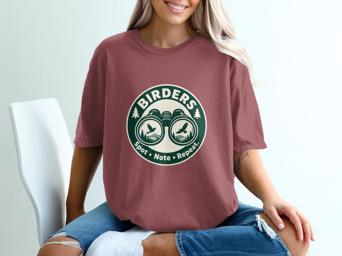 Maroon t-shirt with circular graphic featuring binoculars, birds, trees, and text: BIRDERS, Spot, Note, Repeat.