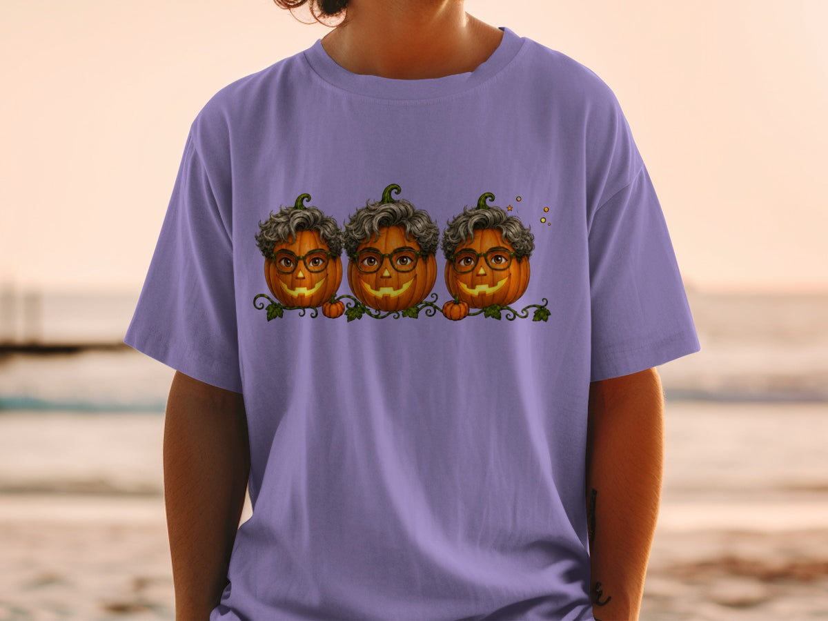 Three jack-o'-lanterns with curly hair and glasses on a purple t-shirt.