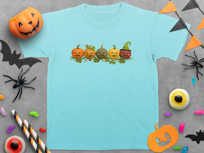 Light blue t-shirt with a row of five smiling pumpkins, one wearing a witch hat.