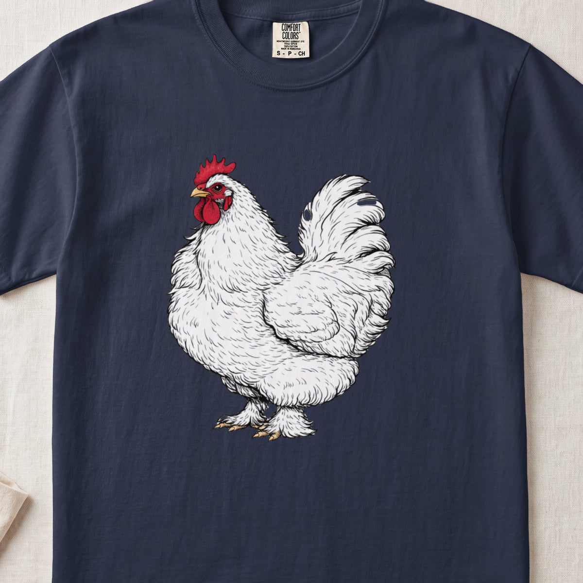 A dark blue t-shirt featuring a detailed illustration of a fluffy white rooster with a red comb and wattle.