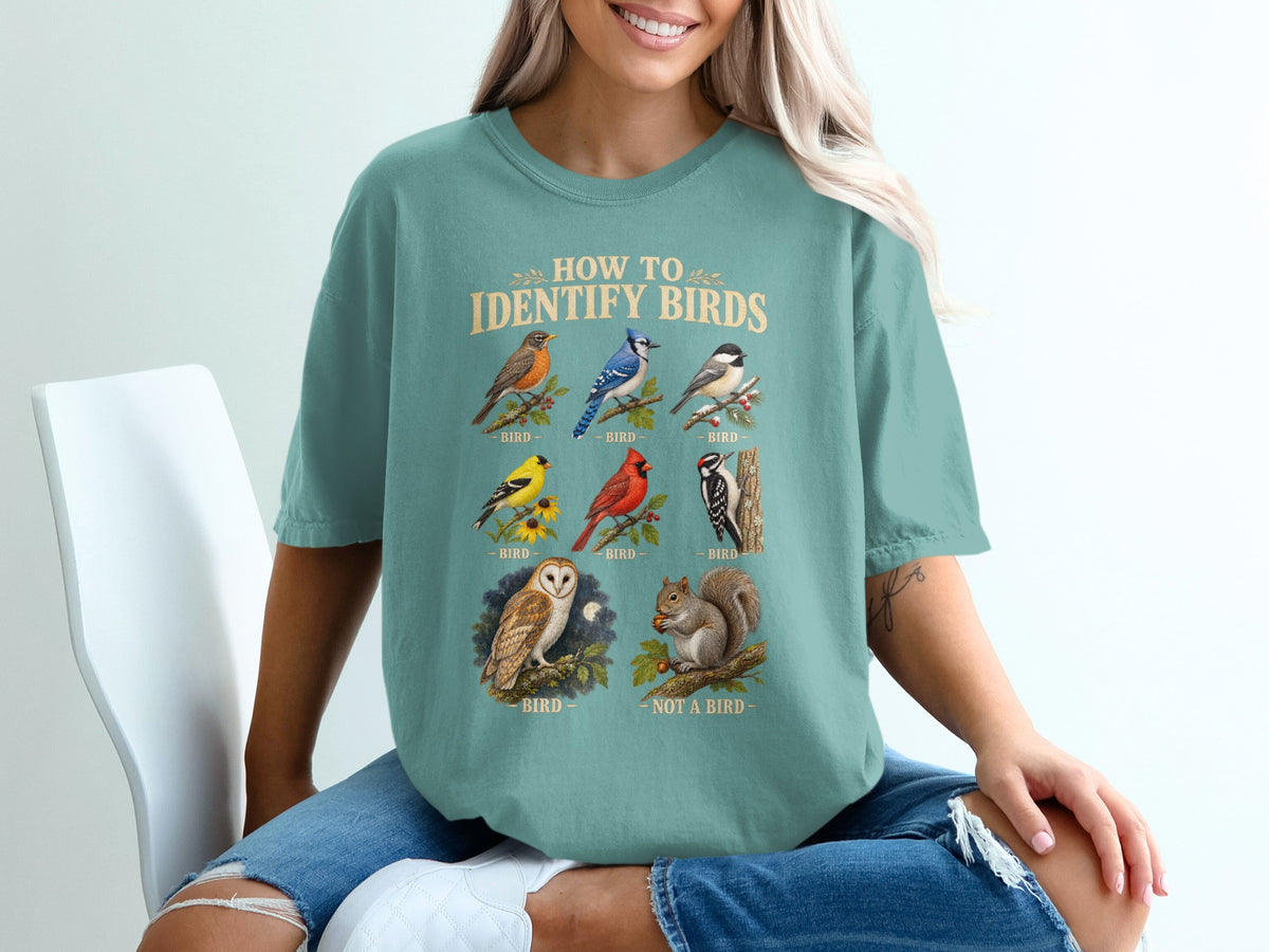 Teal t-shirt with "How to Identify Birds" text and illustrations of birds and a squirrel.