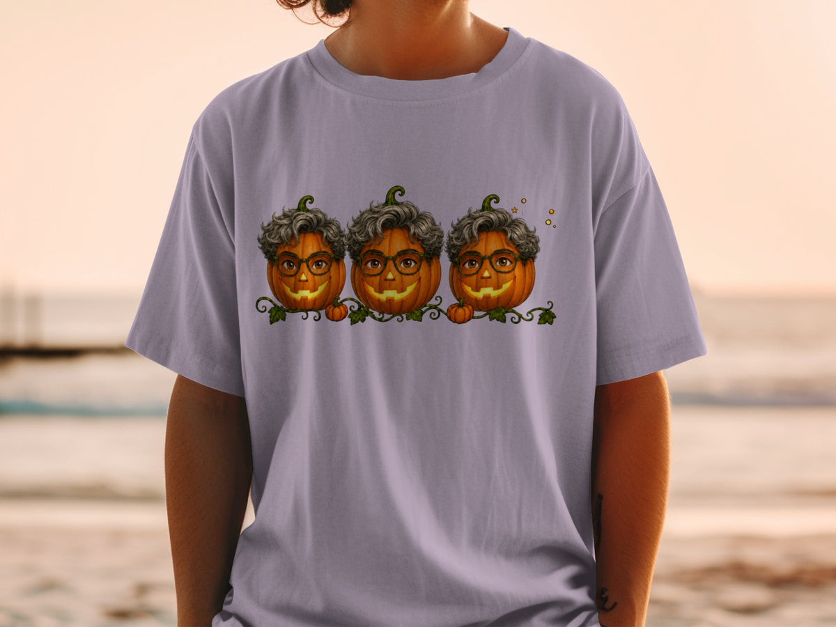 Three jack-o'-lanterns with curly gray hair and glasses on a lavender t-shirt.