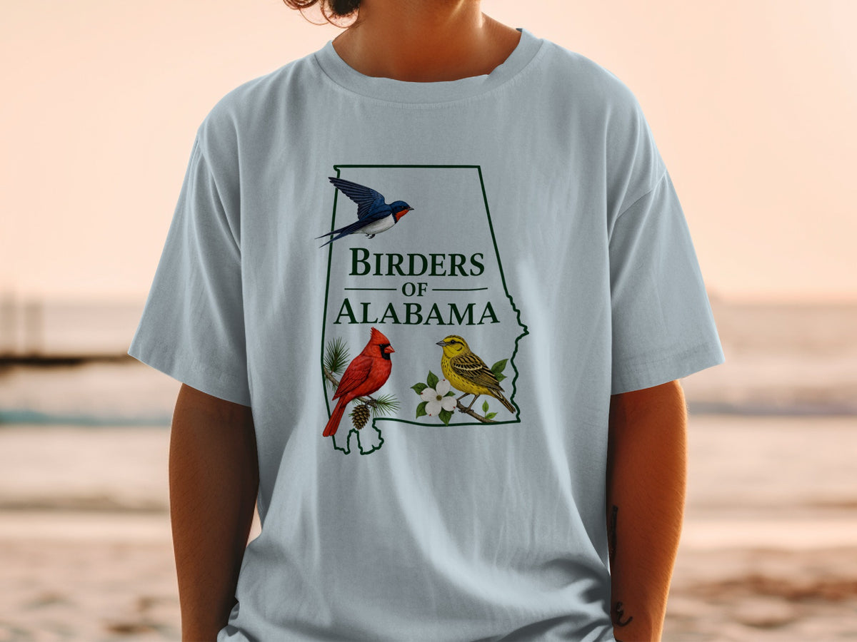 Light blue t-shirt with "Birders of Alabama" text and illustrations of three birds and dogwood flowers.