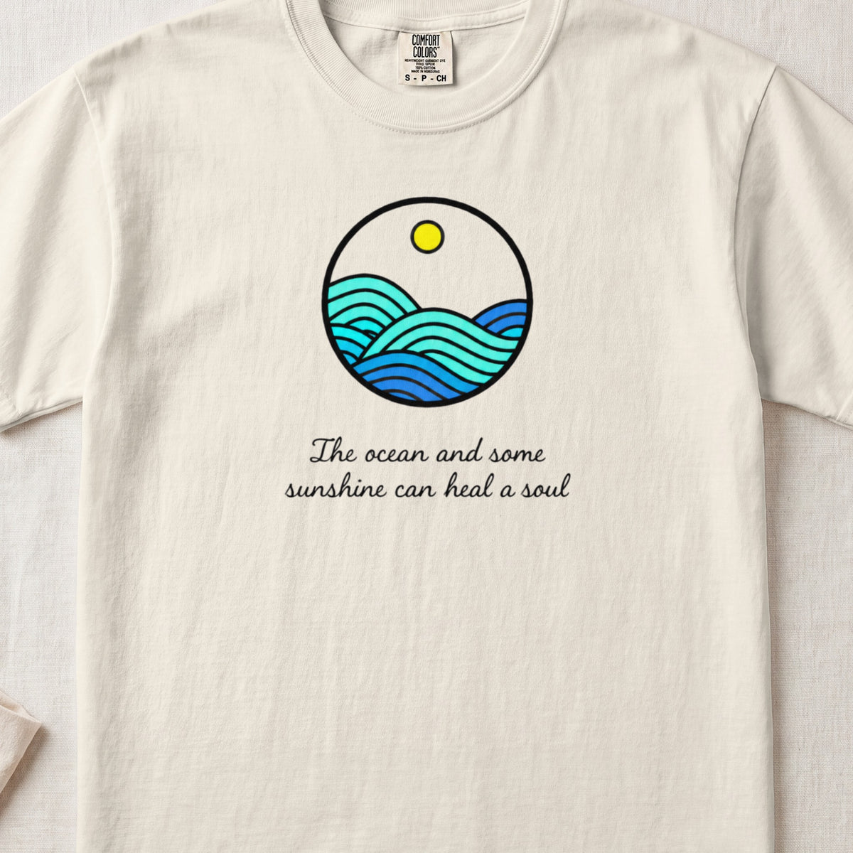 Off-white crewneck t-shirt featuring a circular ocean graphic and the text The ocean and some sunshine can heal a soul.