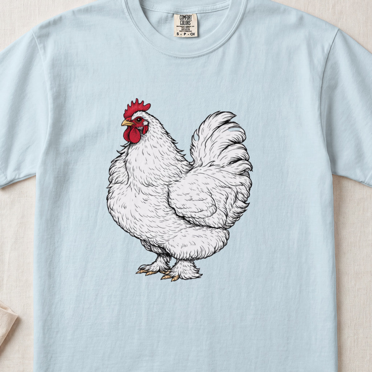 A light blue t-shirt printed with a vintage-style illustration of a white rooster.